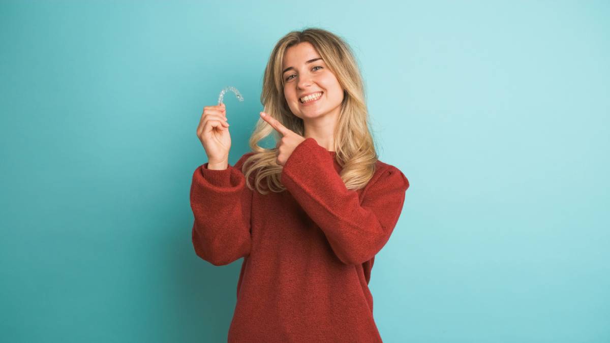 woman holding invisalign and smiling about health benefits of invisalign